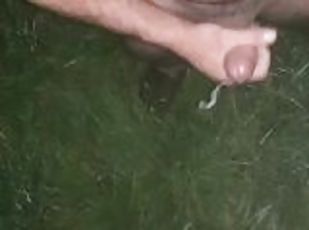 Uncut cock ejaculating a huge load onto the lush green grass in boots and t-shirt