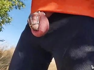 Locked in chastity cage cyclist man is pissing outdoor