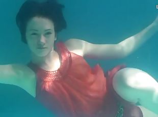 Mermaid dressed in red Rusalka swimming in the pool