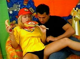 A hot blonde in a t-shirt fucks a guy while sucking her toy